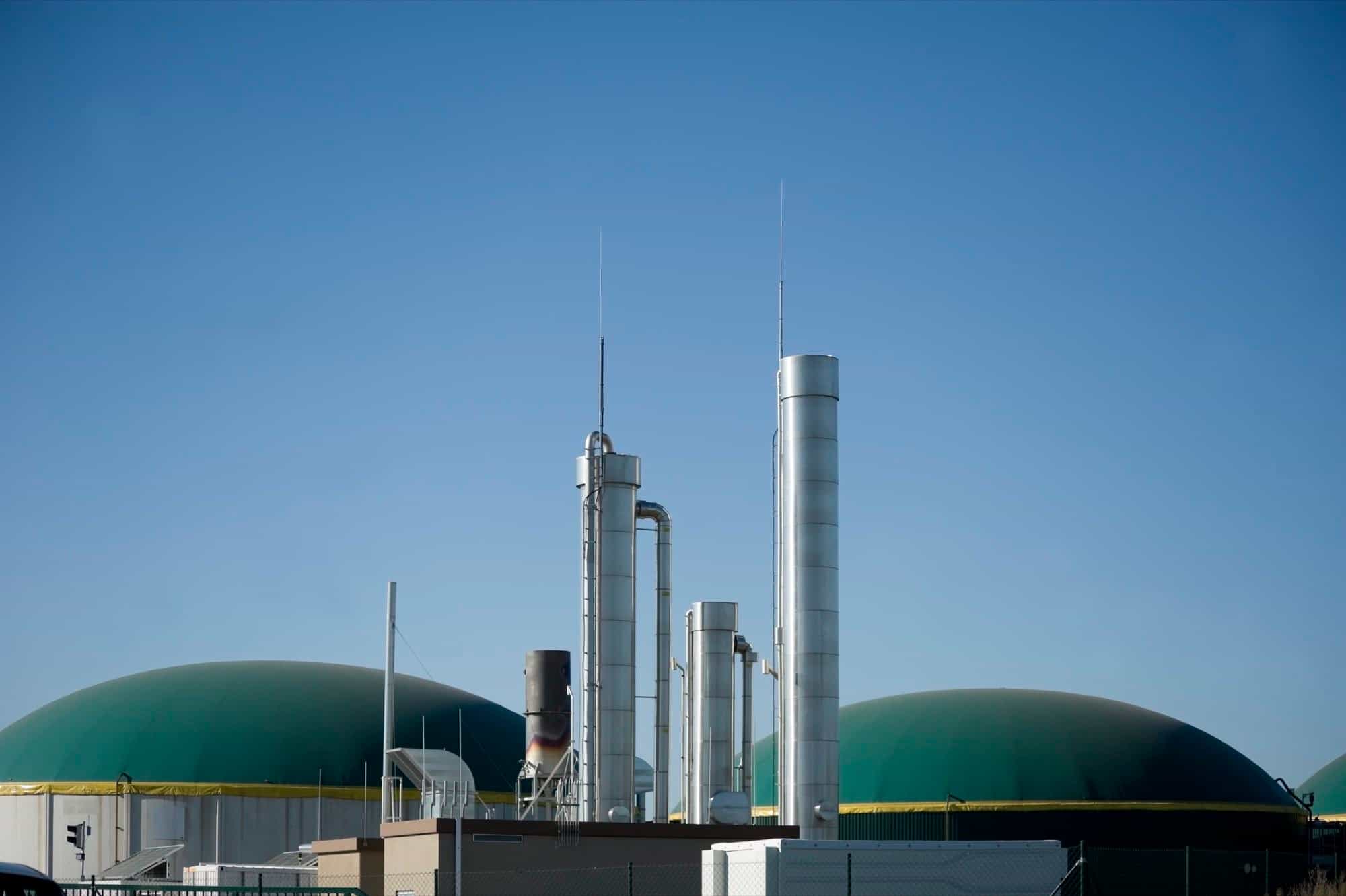 Green biogas domes and steel stacks at a renewable energy plant Green biogas domes and steel stacks at a renewable energy plant